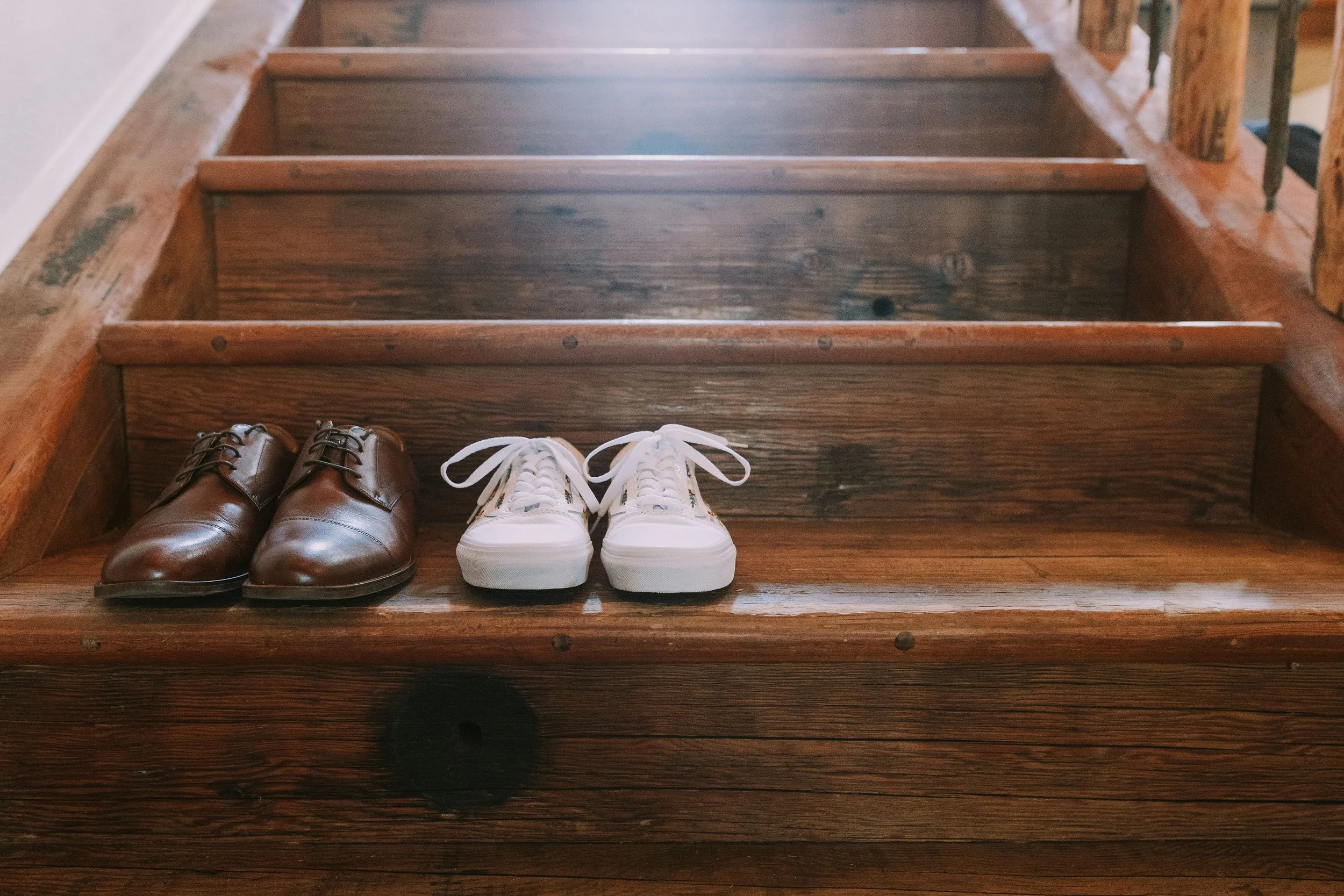 Leather dress shoes and white sneakers paired on a staircase on Jasmin and Grant's Wimberley, Texas wedding morning
